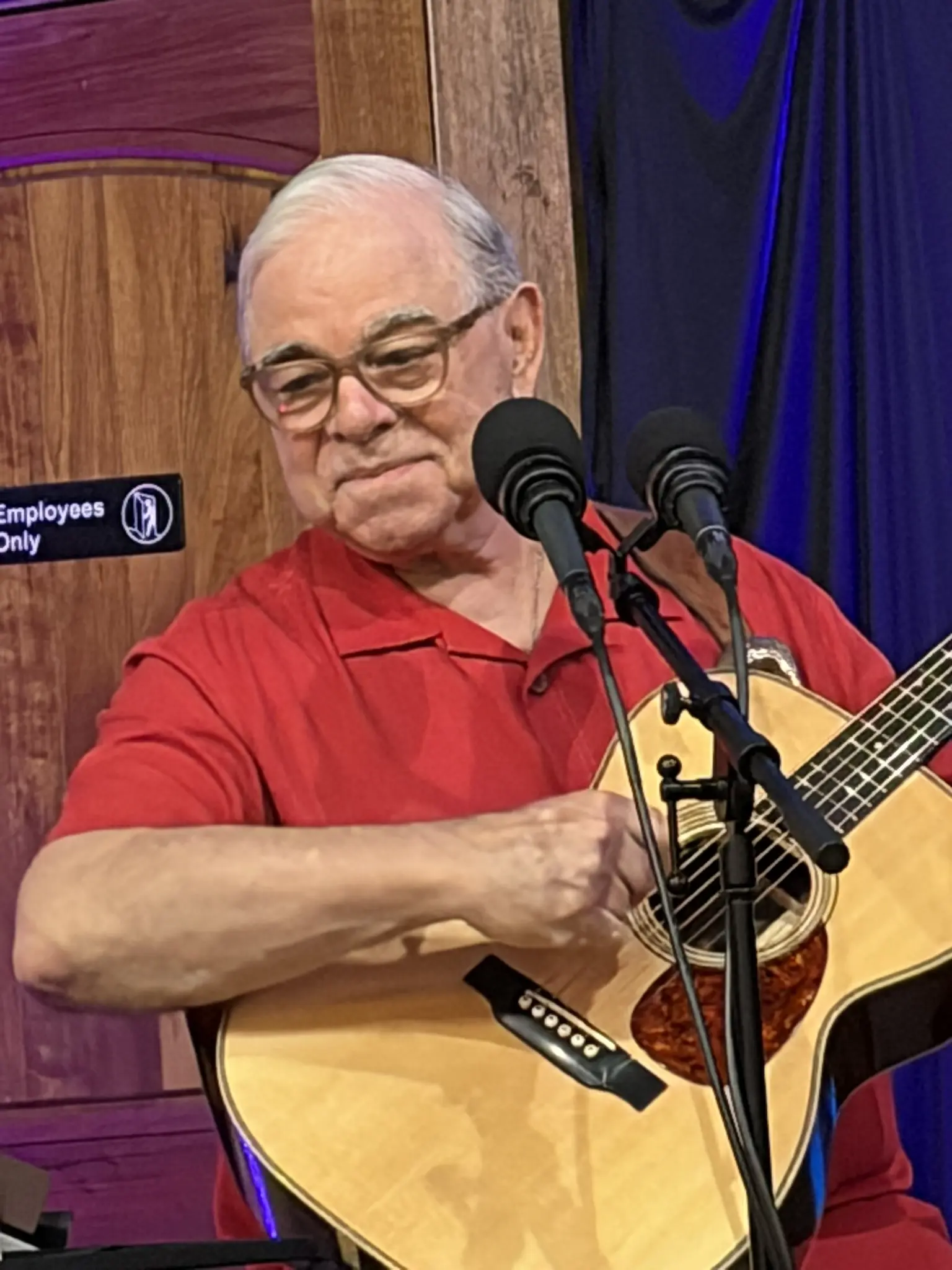 Dave Miller playing guitar at microphone, blue stage curtain
